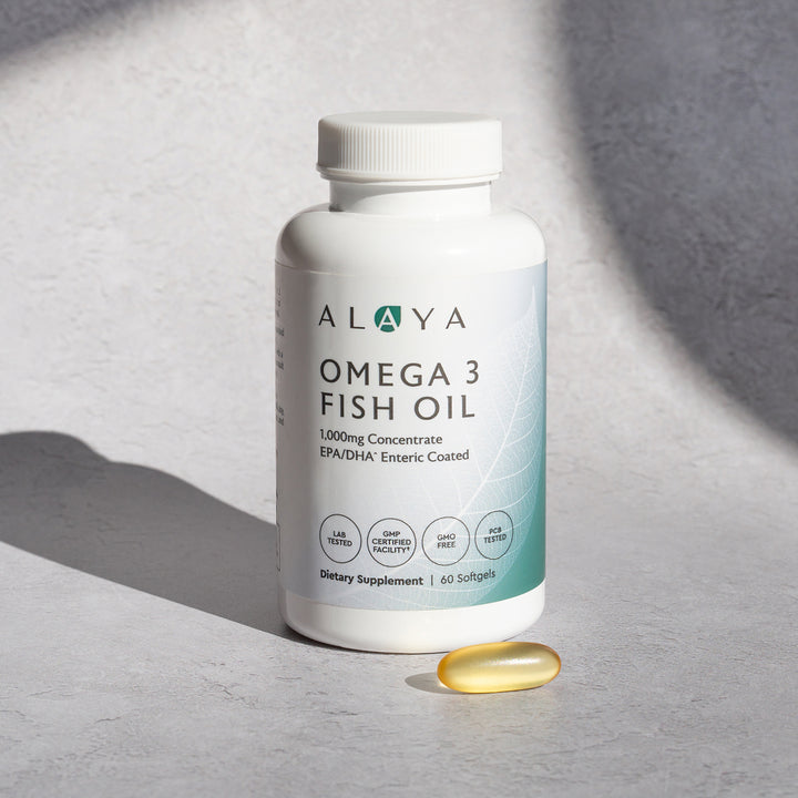Alaya Omega 3 Fish Oil supplement bottle on a gray background with a softgel beside it